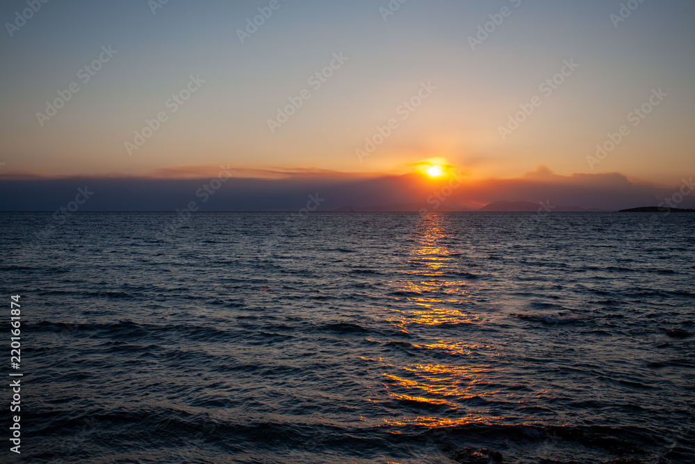 Obraz premium Sun setting behind distant islands on the Aegean Sea horizon