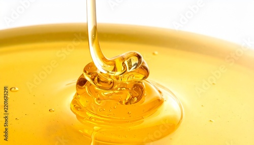 A macro close up view of golden liquid honey pouring into a pool creating beautiful swirling patterns and bubbles on a clean white background.