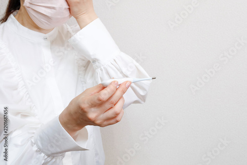 Fototapeta マスクをした女性 体温計を見る様子