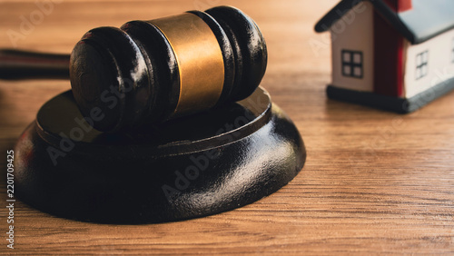 Wooden judge gavel and house model on desk for real estate law concept