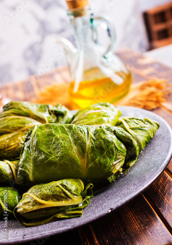 cabbage leaves with minced meat, rice, onion, spices on wooden table. Traditional Eastern European food preparation concept.