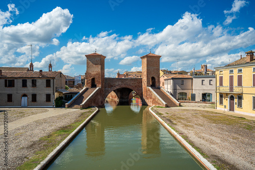 The monumental Trepponti bridge reflected in the central canal of Comacchio, Italy