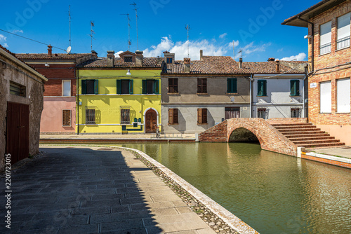 Historic canal with brick bridge and colorful houses in the center of Comacchio, Italy
