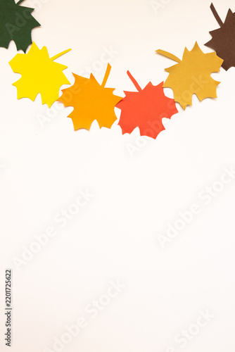 Autumn leaves made of paper forming a garland on a white background, with ample open space for messages, advertising, graphic design, and seasonal content
