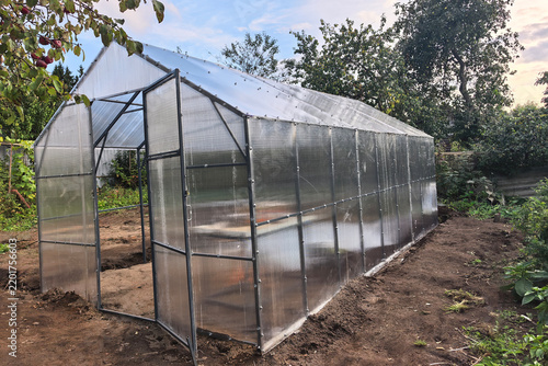 vGreenhouse built in a garden with framing and panels in a rural area during daylight