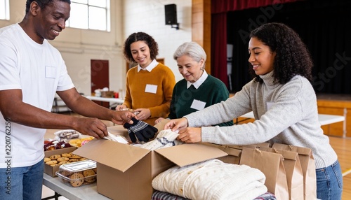 Diverse group of volunteers packing warm clothes and food into donation boxes in a community hall, supporting local charity drive and social relief outreach