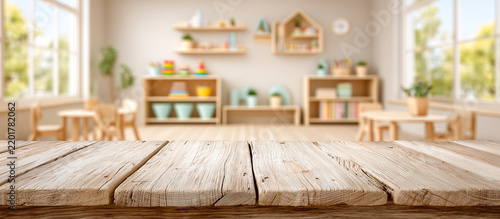 Light oak wooden tabletop in the foreground with a softly blurred modern kindergarten classroom in the background, creating a clean educational setting.