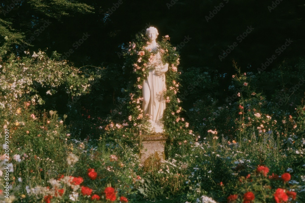 Obraz premium Statue surrounded by lush blooming flowers in a dreamy garden