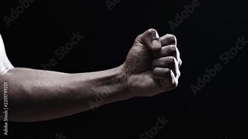 Man hand clenching into fist and opening palm on black background