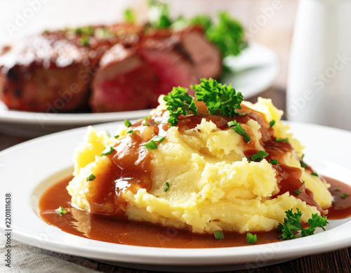 Homemade mashed potatoes with gravy, white plate, closeup. AI