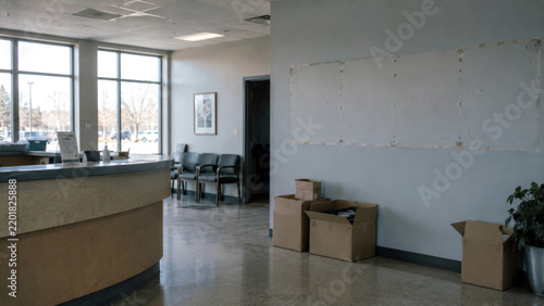 Empty office reception area with moving boxes and marks from removed wall signage, representing business closure, relocation, vacancy, and organizational change