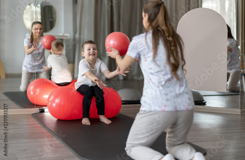 Child Physical Therapy Session With Therapist Using Red Exercise Ball In Pediatric Rehab Clinic