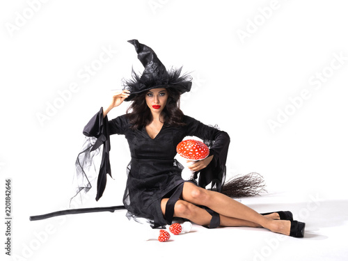 A beautiful witch in a black dress flies on a broomstick