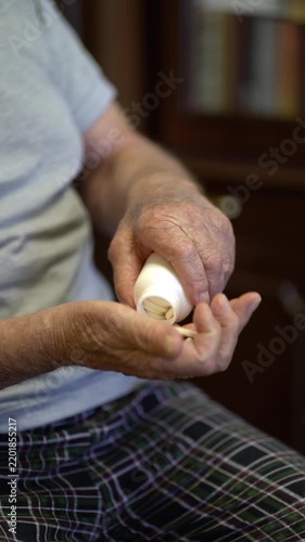 Close-up of aged man taking medication from white bottle into hand. Retirement health and daily pills.