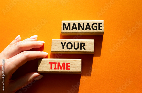  Concept words manage your time on wooden blocks arranged as steps. Businessman hand arranging wooden blocks. Time management and productivity concept. Orange background. Copy space.