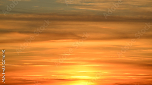 фотографія The golden light of the setting sun reflected off the thick layer of altostratus clouds