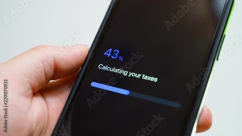 Hand holding smartphone with tax app progress bar stuck at 70 percent while calculating taxes