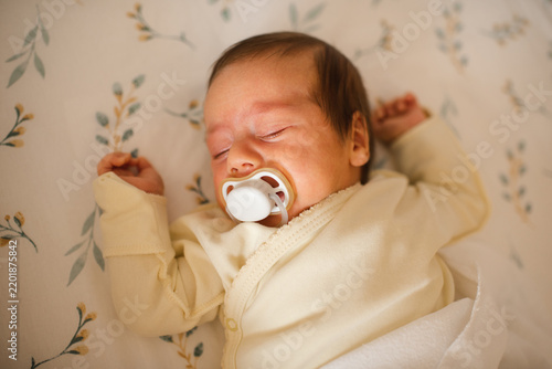 Cute infant baby sleeping in crib with pacifier close up top view. Childhood.
