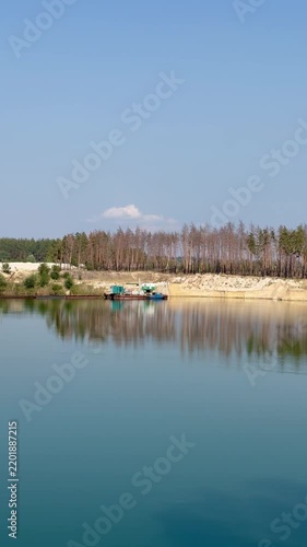 Serene Quarry Lake with Industrial Barge and Pine Forest Reflection
