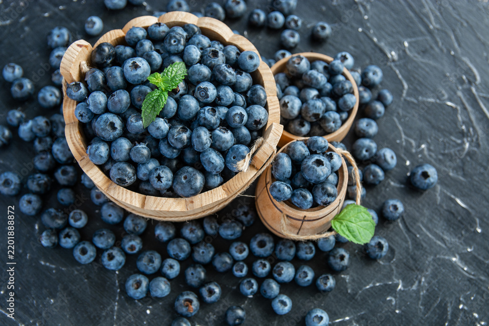 Obraz premium fresh ripe blueberries on a dark textured background. Healthy organic summer berries with green mint leaves.
