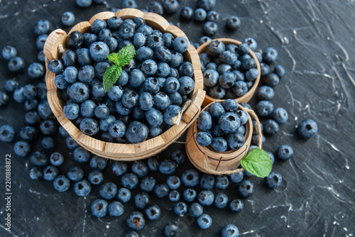 fresh ripe blueberries on a dark textured background. Healthy organic summer berries with green mint leaves.