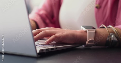 Hands are typing on laptop keyboard at desk as right hand is lowering to edit document