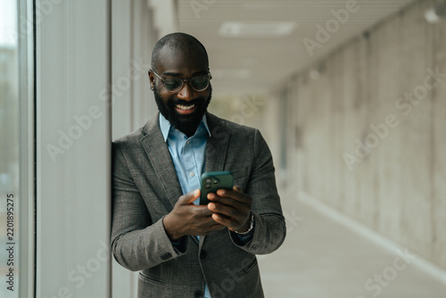 Black businessman smiling and using smartphone for communication