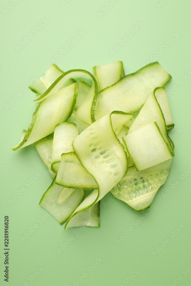Obraz premium Slices of ripe cucumber on green background, top view