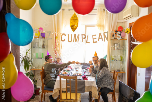 Canvas Print family toasting at a decorated table during a festive birthday celebration at Spanish home with cumpleaños word in decorations