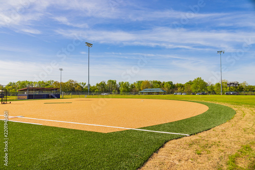 An empty baseball diamond sits under a bright blue sky.
