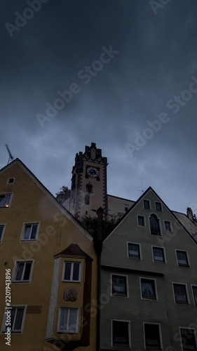 Hohes Schloss castle clock tower rising above historic gabled houses in Füssen, Bavaria, Germany