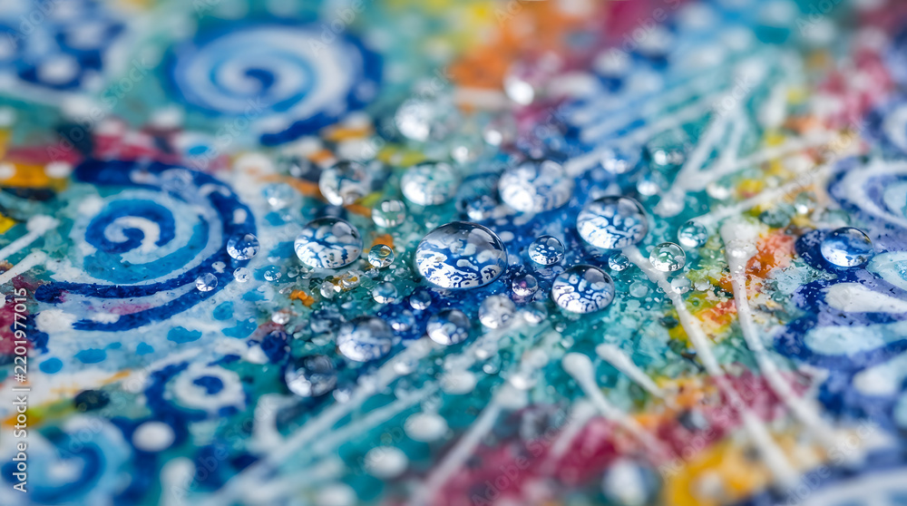 Fototapeta premium Macro view of clear water droplets resting on a colorful abstract textured artistic painted surface with vibrant blue swirls and paint splatters