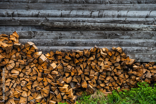 Stacked firewood against a rustic wooden wall