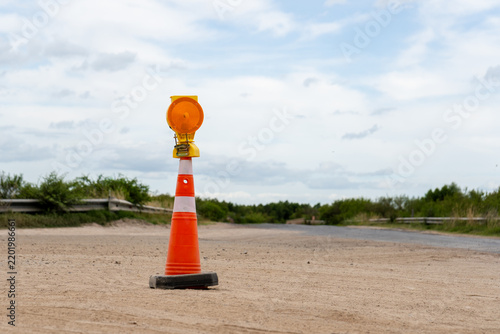 Traffic safety cone with warning light on a rural paved road