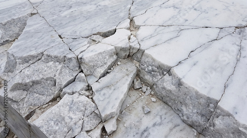 Broken white marble slabs with natural grey veining and jagged cracks on a construction site