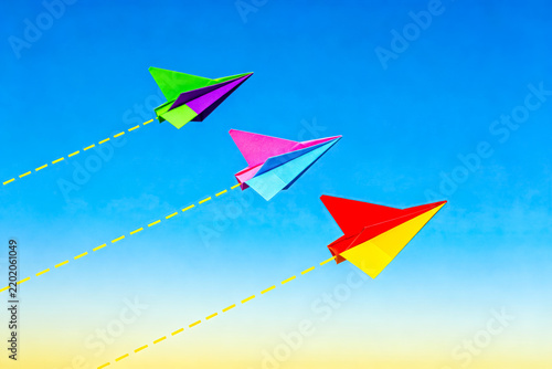 Three Colorful Paper Planes Flying in Clear Blue Sky