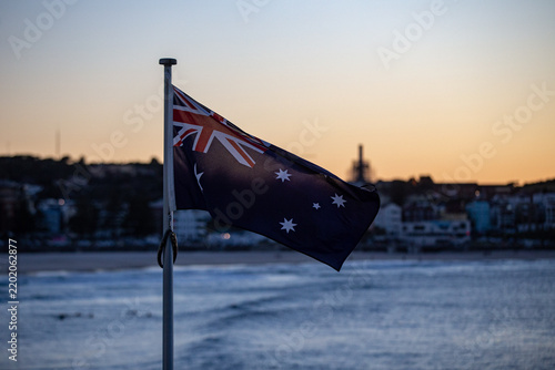Australian flag fluttering gently on a flagpole near the coast during sunset