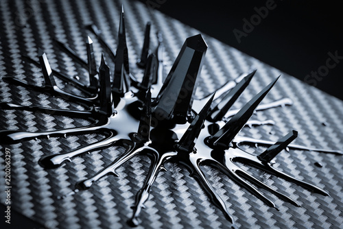 Schwarzes Ferrofluid formt magnetische Spitzen auf Kohlefaser, Makro