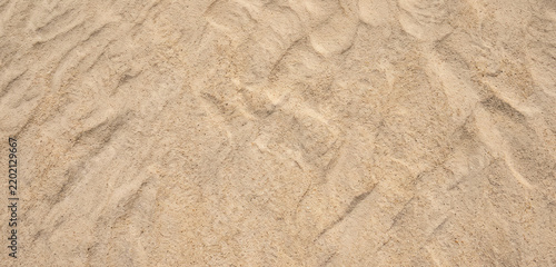 A close-up view of sandy terrain showing fine grains, subtle textures, and natural patterns formed by wind and movement.