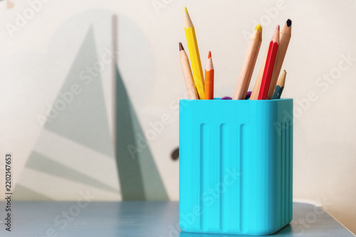 Colorful pencils in a turquoise holder on a desk. Sharp art supplies for education, creative workspace, and back to school marketing materials