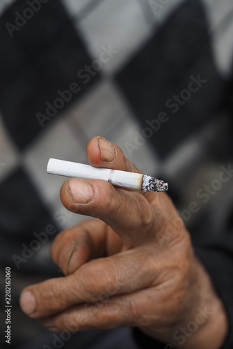 Foto Man holding a cigarette with ash at the tip in a close view