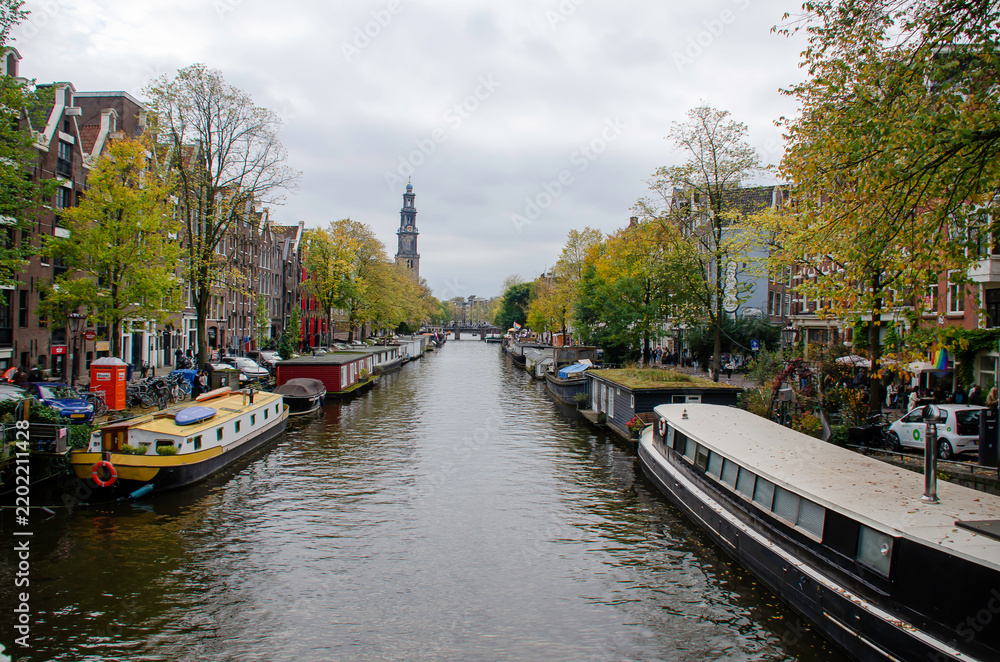 Fototapeta premium Amsterdam, with its historic canals and houseboats, reveals the charming architecture, vibrant urban life, and unique atmosphere that characterize this Dutch city.