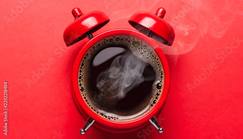 Top-Down View of a Steaming Cup of Coffee in a Classic Red Alarm Clock on Vibrant Red Background