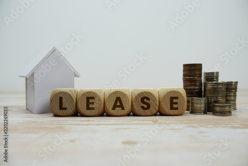 LEASE alphabet letters with house model and coin stack Properties and Real Estate Concept