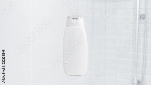 Blank white shampoo bottle with disc cap in modern shower
