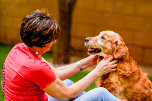 Woman petting golden retriever in backyard showing friendship