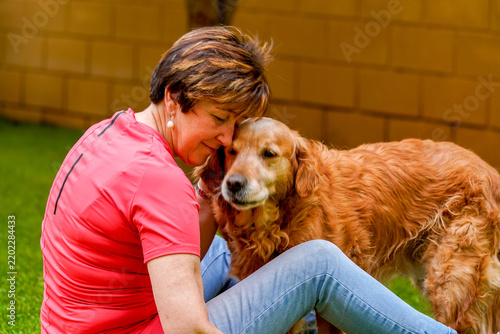 Woman bonding with golden retriever dog in yard