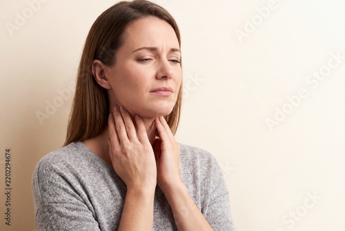 Woman Touching Sore Throat Experiencing Pain From Cold or Flu