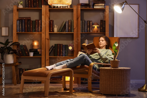 Relaxation and leisure time, young woman reading a book in a comfortable armc...