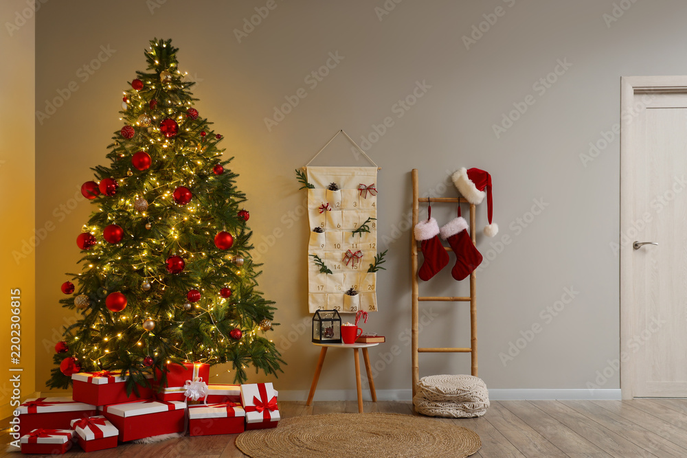 Obraz premium Christmas holiday preparation and festive home interior, decorated pine tree with gift boxes and advent calendar in a cozy living room atmosphere